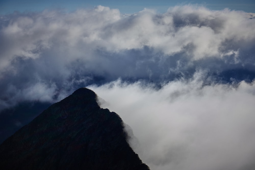 a very tall mountain surrounded by clouds in the sky