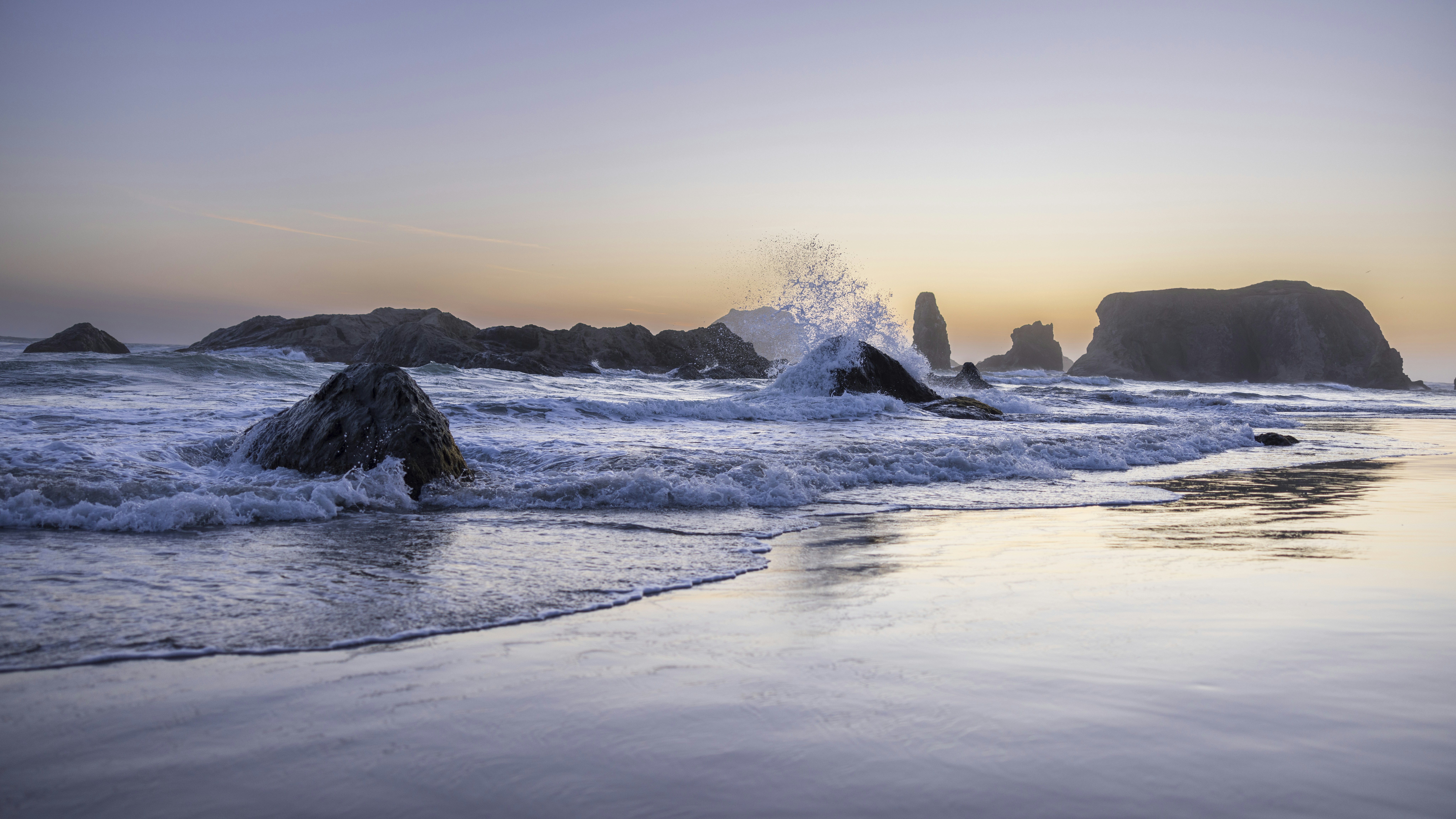 a beach with waves crashing on the rocks