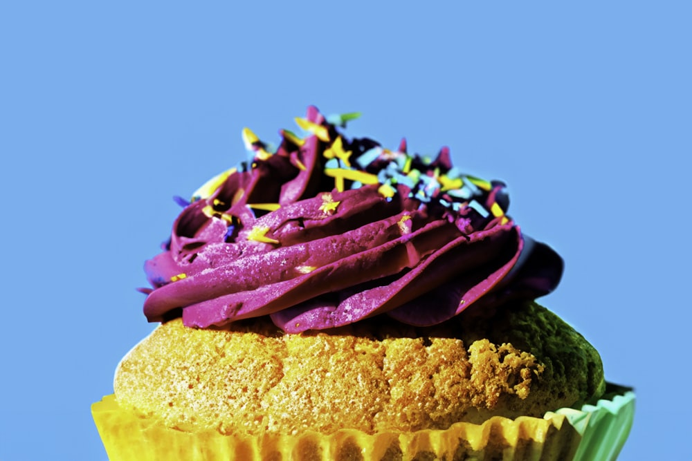 a cupcake with purple frosting and sprinkles