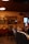 A cozy vintage-themed cafe featuring wooden shelves with various decorative items, including artwork and pottery. Retro signs labeled ‘KAFFE’ and ‘KARSK’ are displayed. A person is seated at a table, using a smartphone, with dim lighting contributing to the warm ambiance.