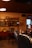 A cozy vintage-themed cafe featuring wooden shelves with various decorative items, including artwork and pottery. Retro signs labeled ‘KAFFE’ and ‘KARSK’ are displayed. A person is seated at a table, using a smartphone, with dim lighting contributing to the warm ambiance.