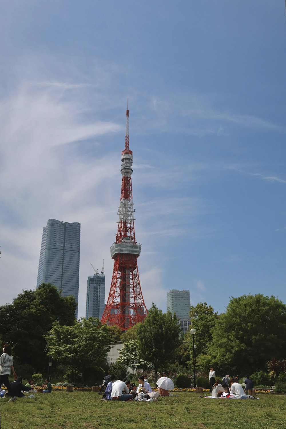 a group of people sitting on the grass in front of a tall tower