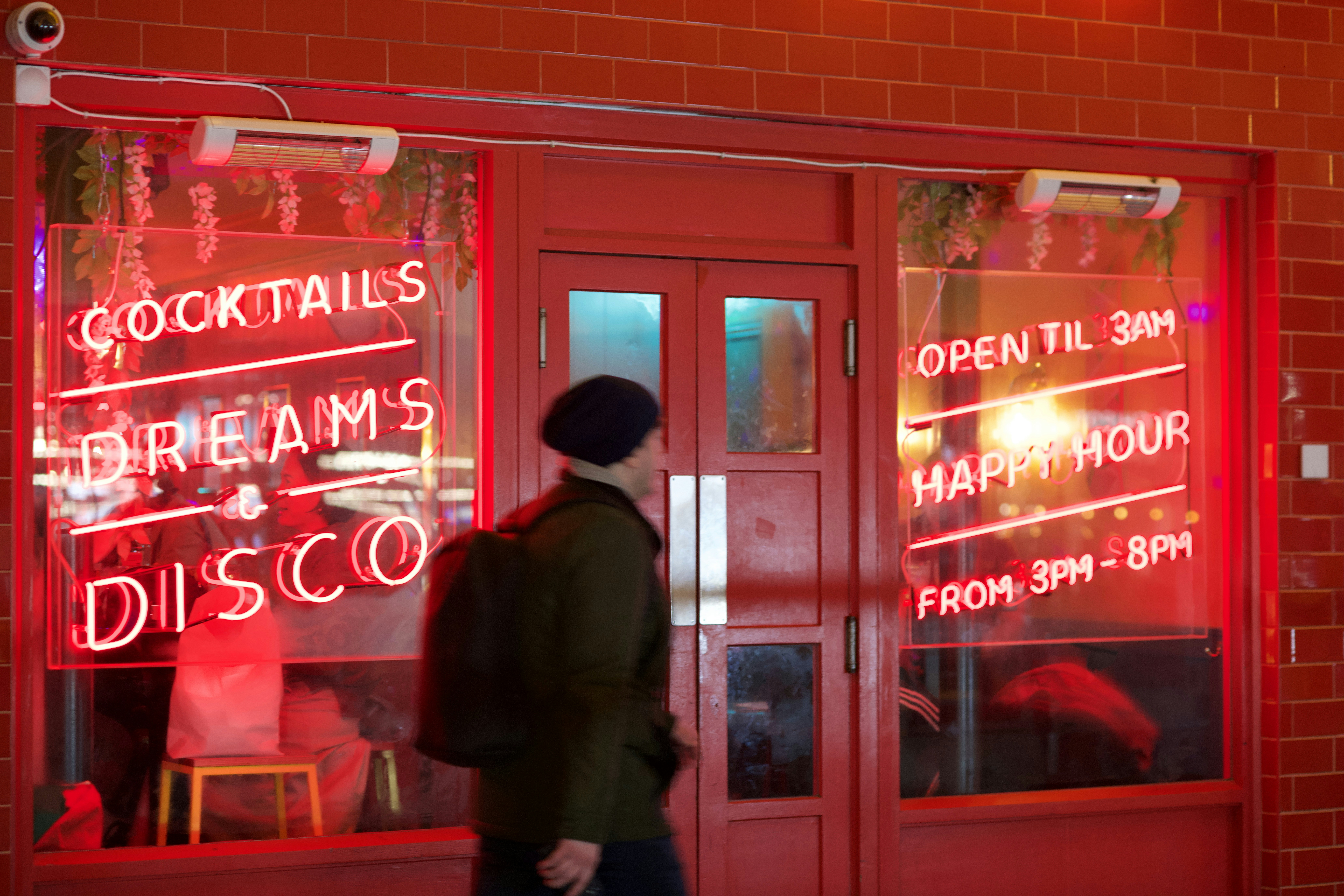 Lively bar interior on Wilton Drive with colorful lighting, cocktails on the bar and happy hour crowd