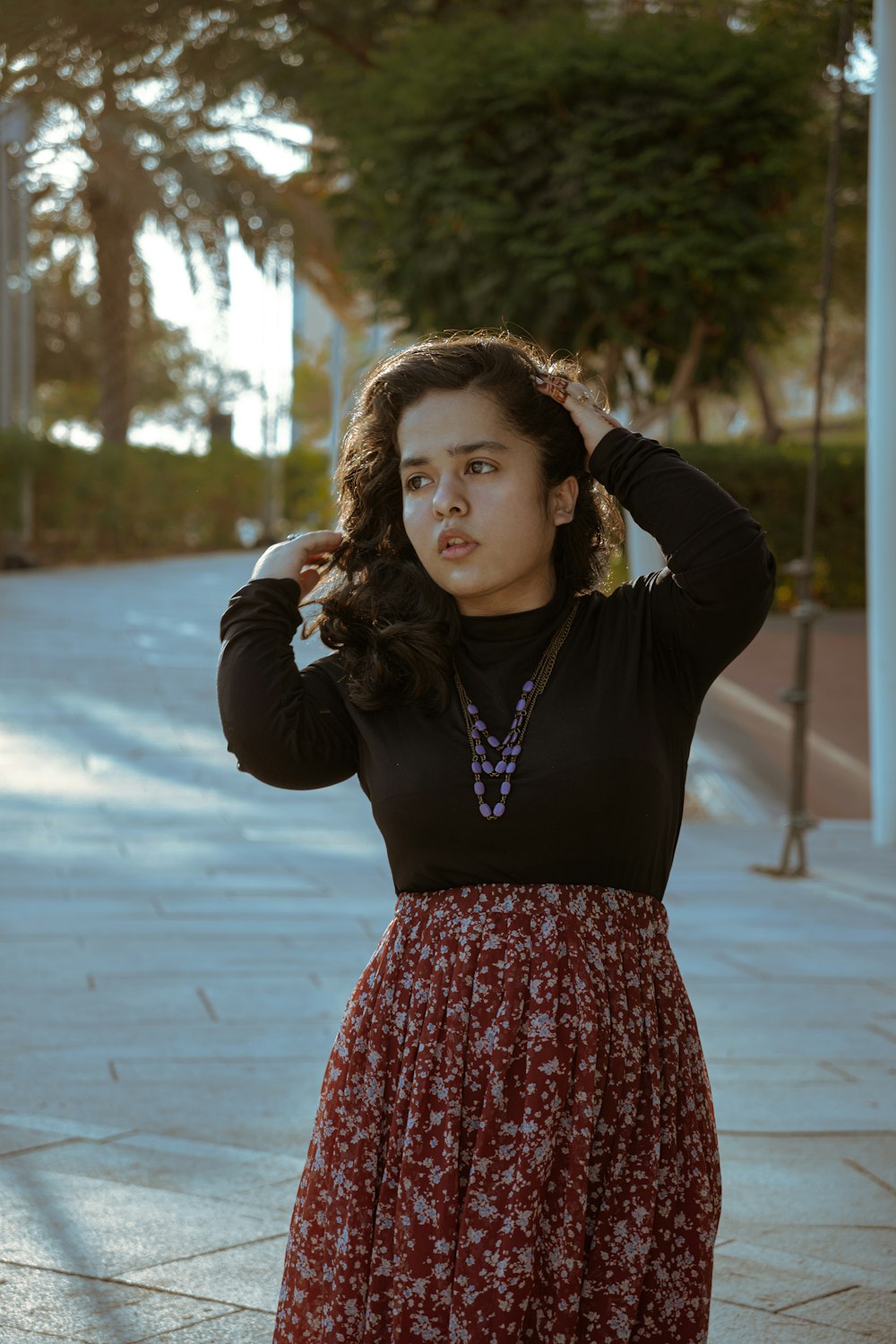 a woman standing on a sidewalk with her hands on her head