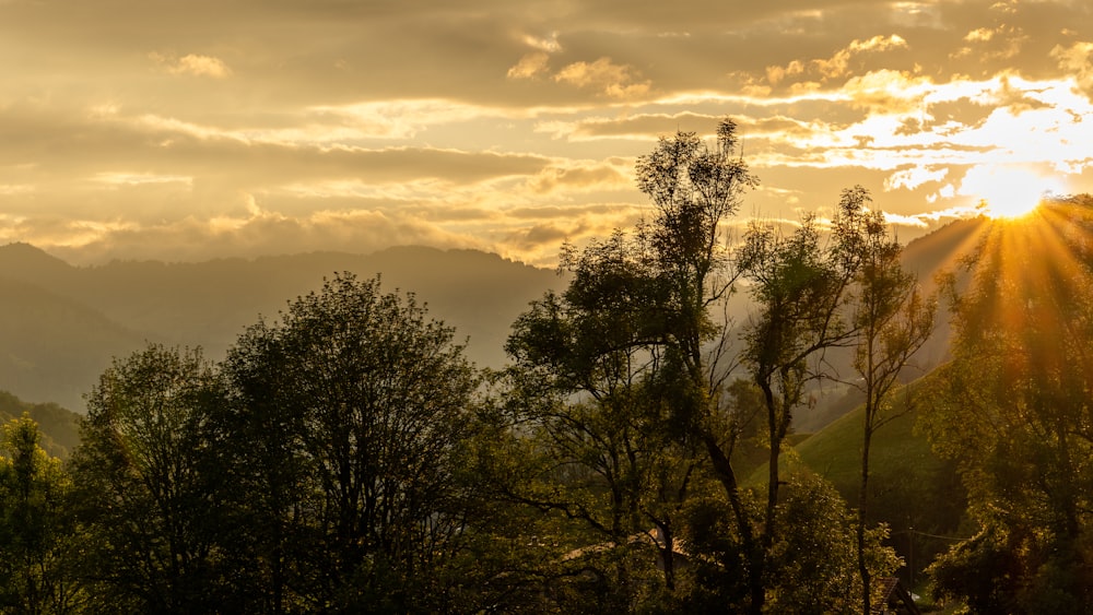 the sun is shining through the clouds over the mountains