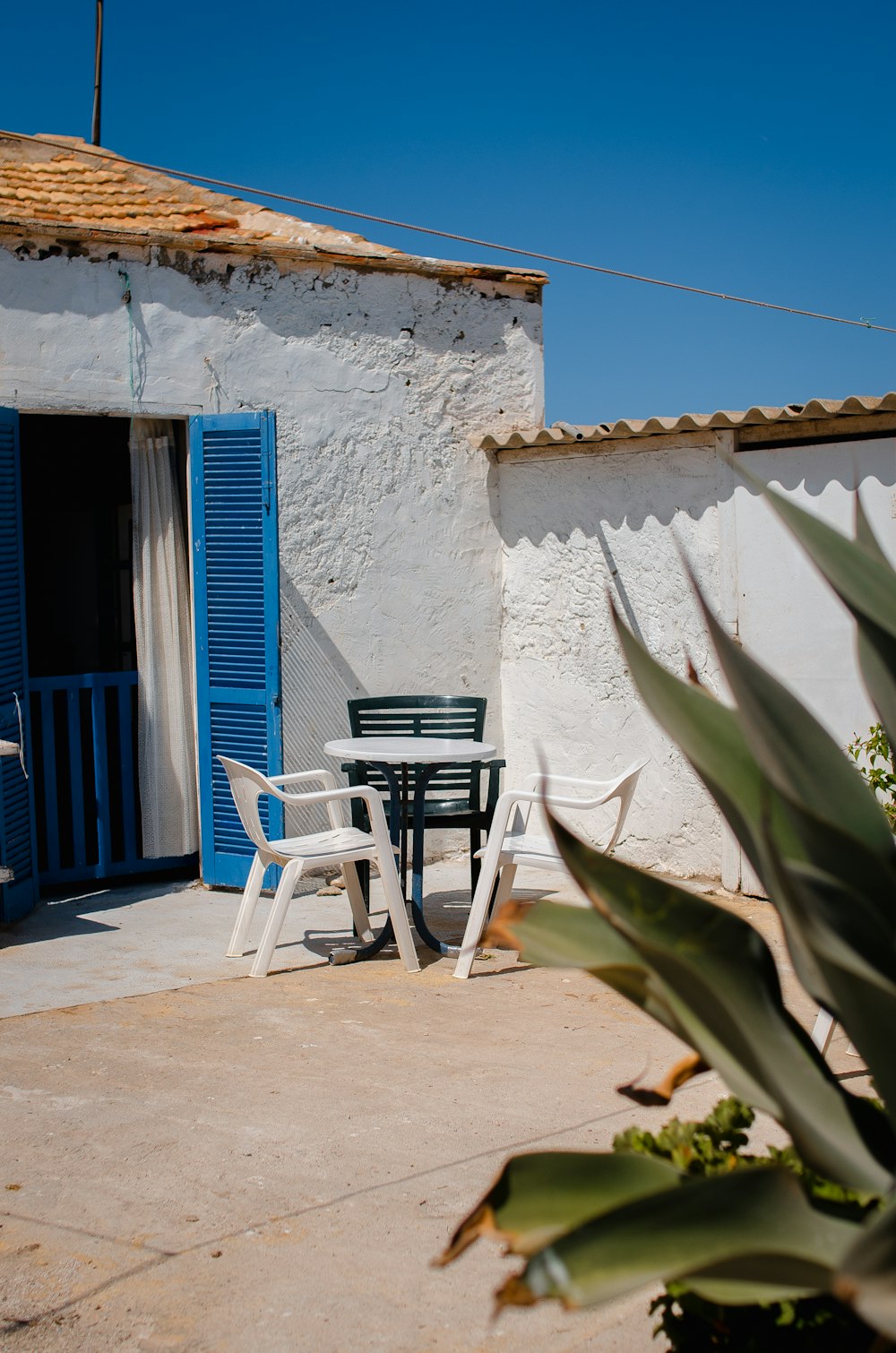 un patio con una mesa y sillas al lado de un edificio