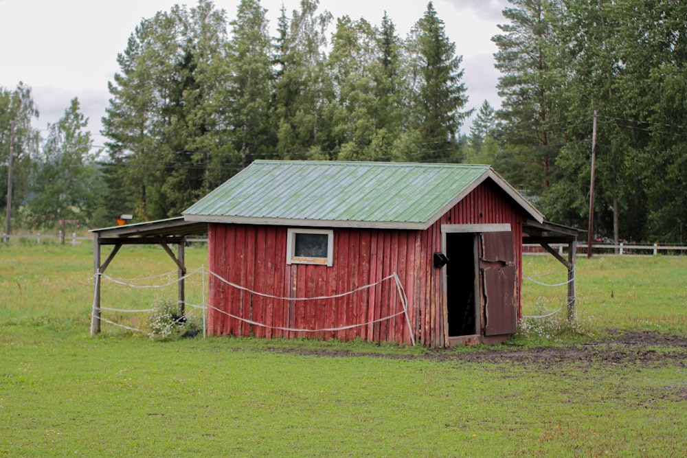a red barn with a green roof in a field