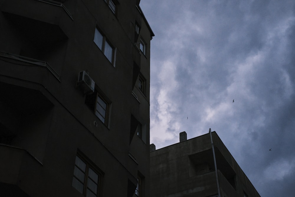 a tall building sitting next to a tall building under a cloudy sky