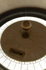Close-up of a pendulum swinging in a physics classroom.