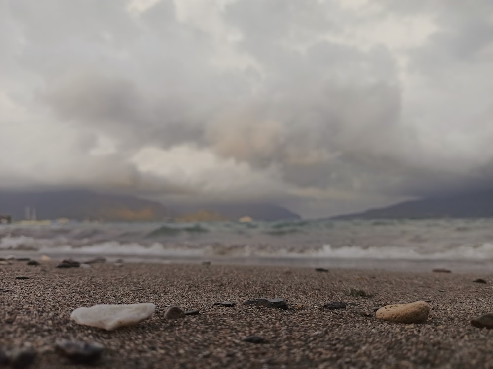 a beach with rocks and water under a cloudy sky