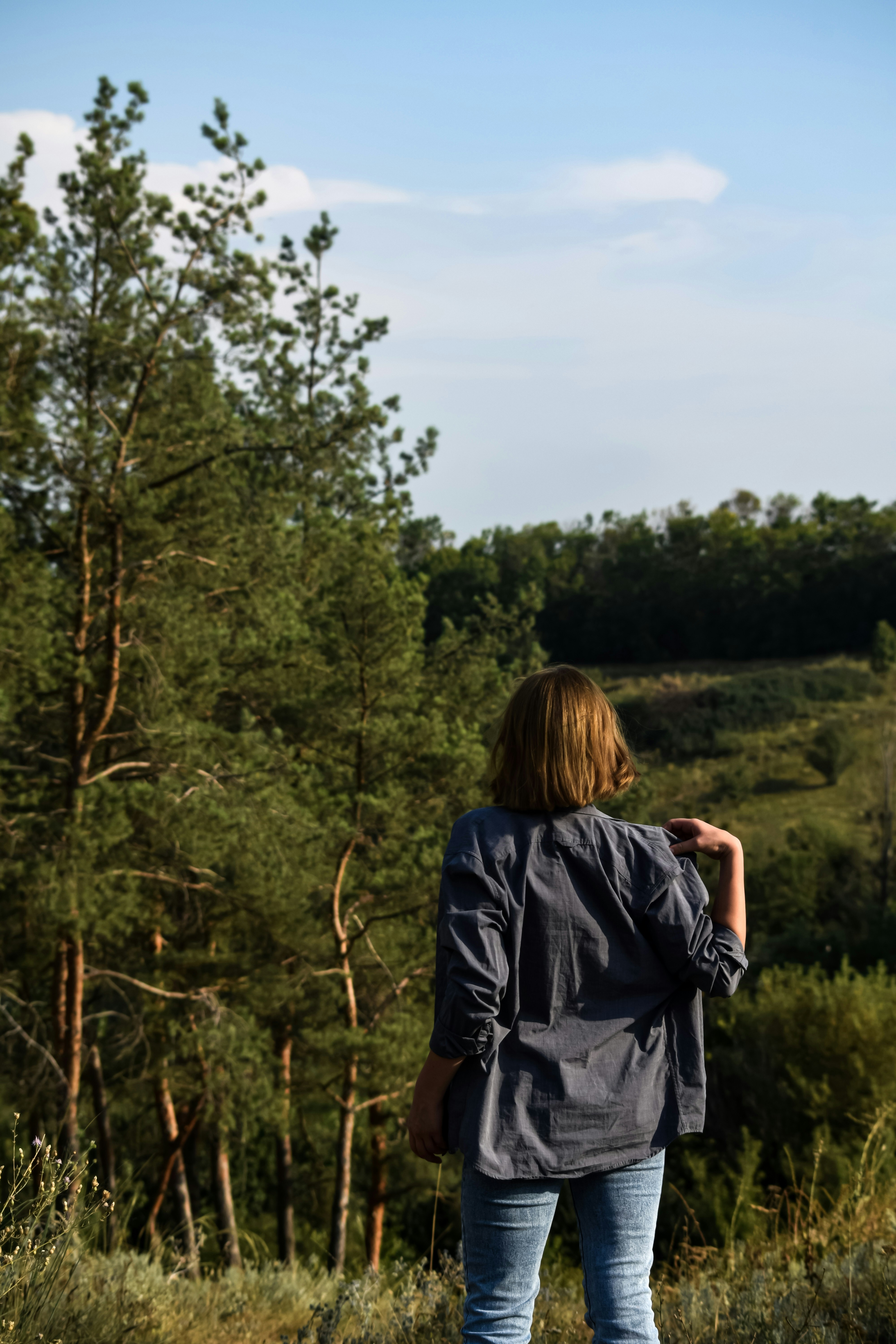 a woman standing in a field with trees in the background