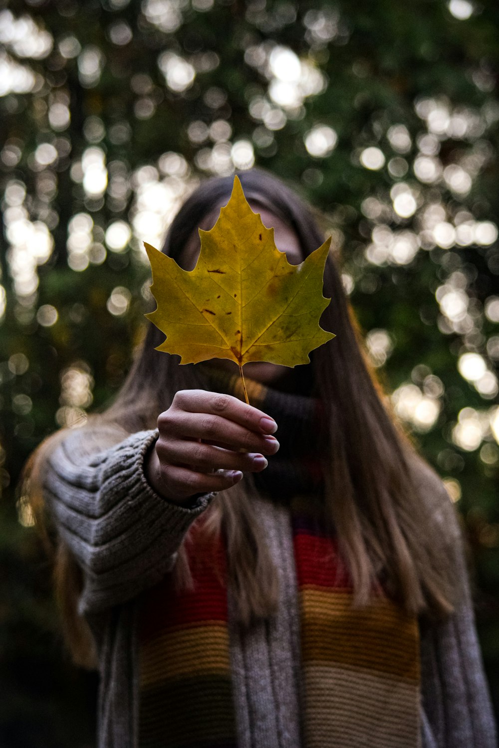 a woman holding a leaf in front of her face