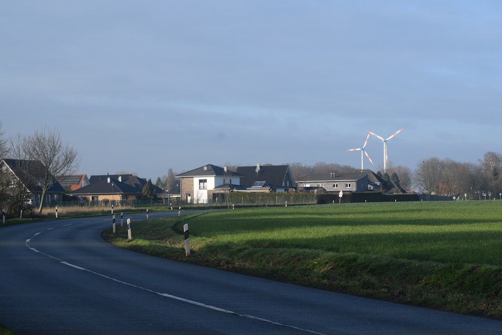 a rural road with houses and windmills in the background