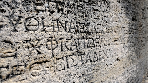 Ancient stone surface with carved inscriptions in a classical language.