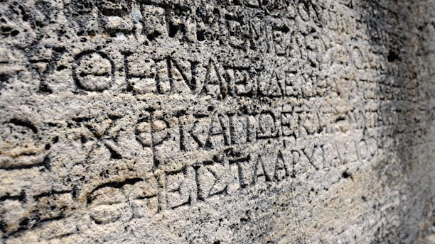 Ancient stone surface with carved inscriptions in a classical language.