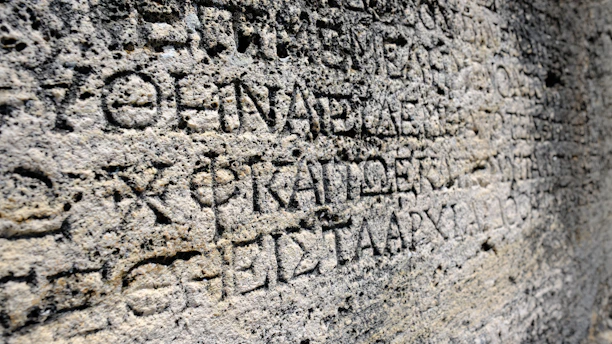 A close-up photograph of an ancient Tamil script carved on a stone tablet.