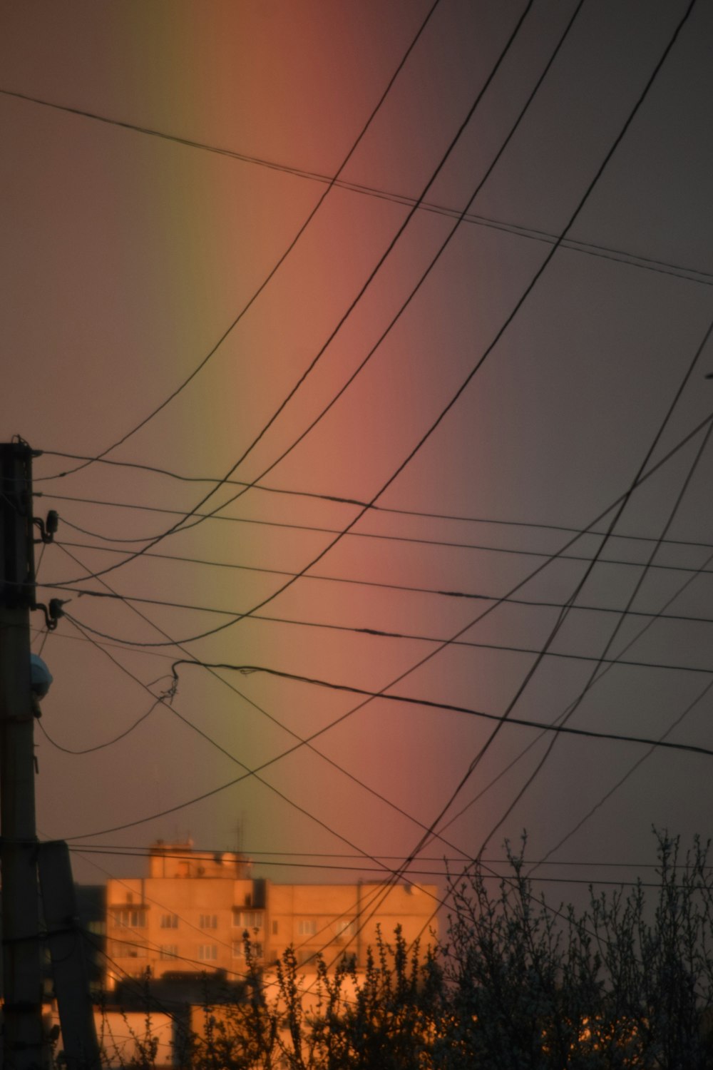 a rainbow in the sky with power lines in the foreground