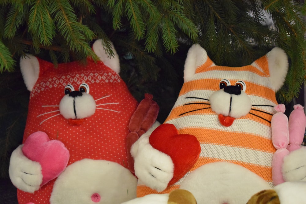 a couple of stuffed animals sitting next to a christmas tree