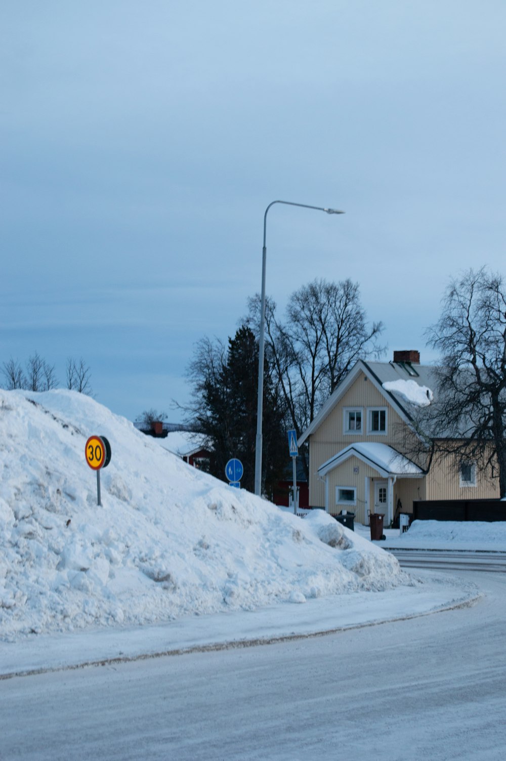 a house on a hill of snow with a street sign in the foreground