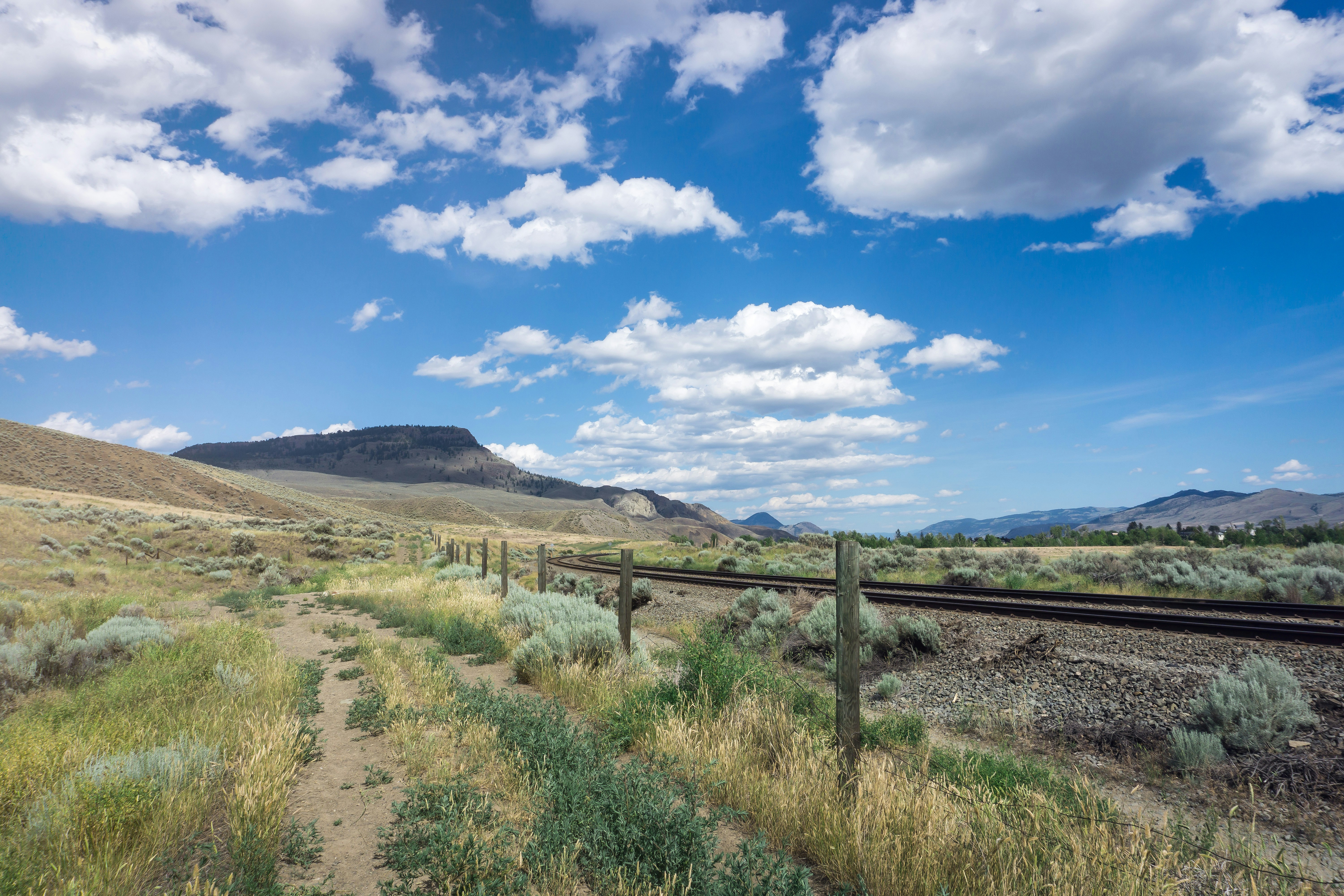 Freight train on railway tracks in open South African landscape, bright daytime scene with blue sky and dry grassland