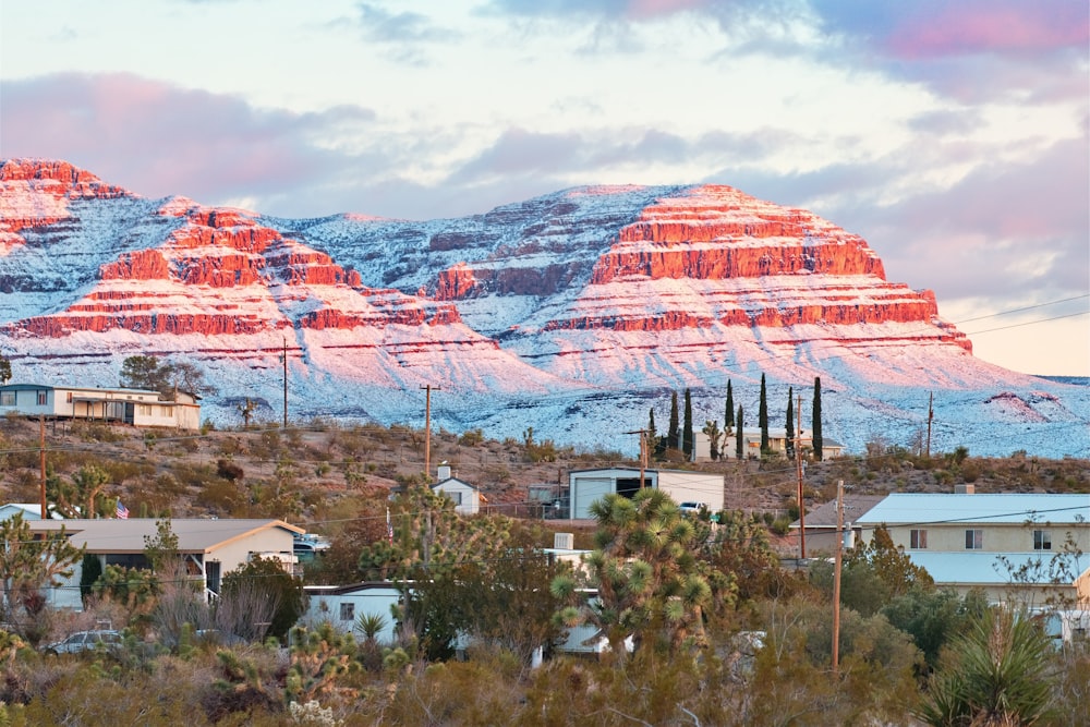 a snow covered mountain range with houses in the foreground