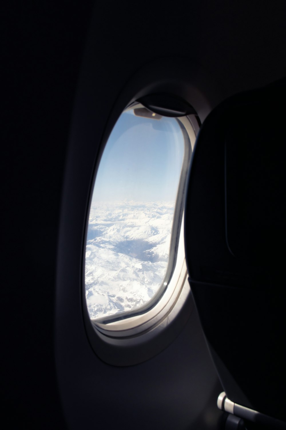 An airplane window with a view of the snow covered mountains photo – Fly  Image on Unsplash