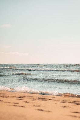 Soft waves gently washing onto a quiet sandy beach under a clear sky