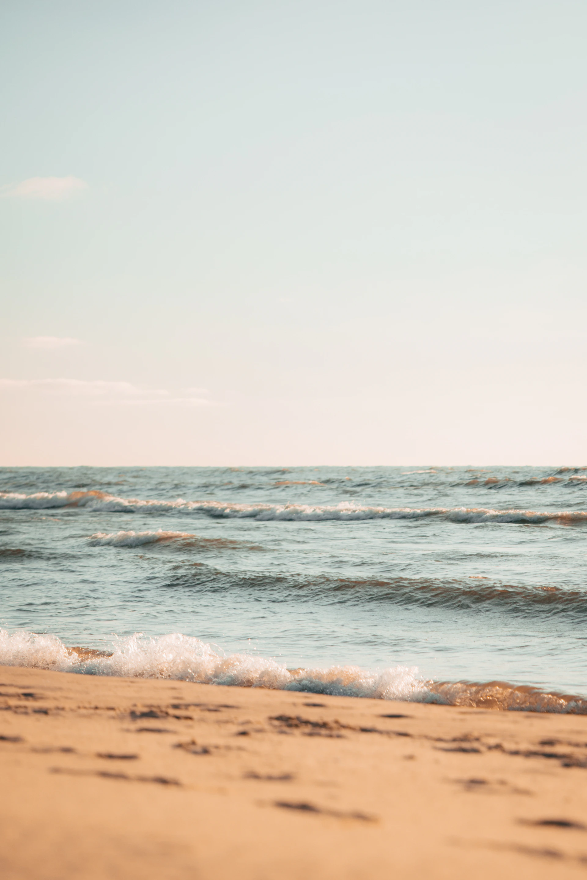 An intimate close-up of crystal-clear ocean waves rolling softly onto the shore, sunlight sparkling on the water’s surface, evoking a serene and immersive coastal vibe.