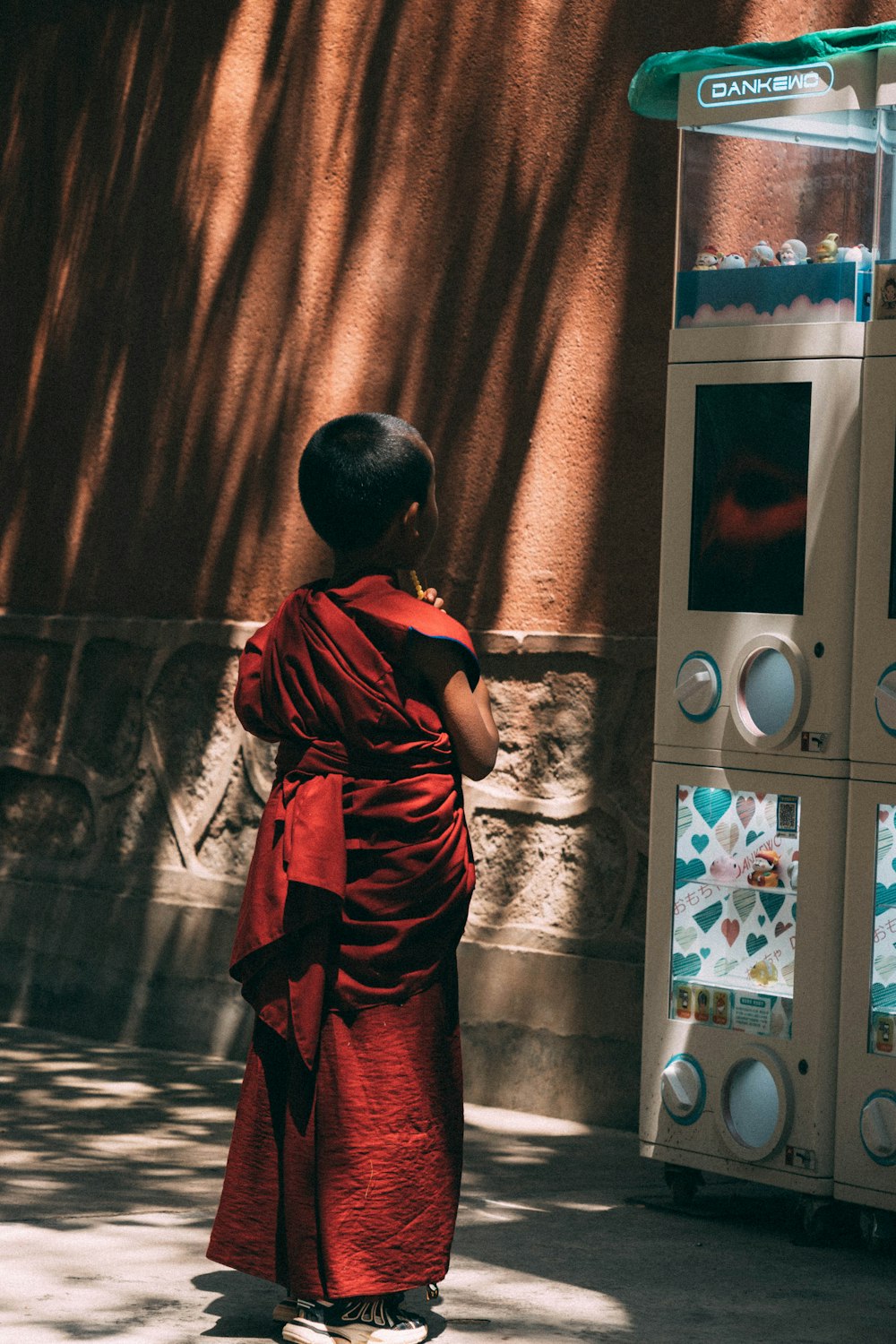 a person in a red robe standing in front of a vending machine