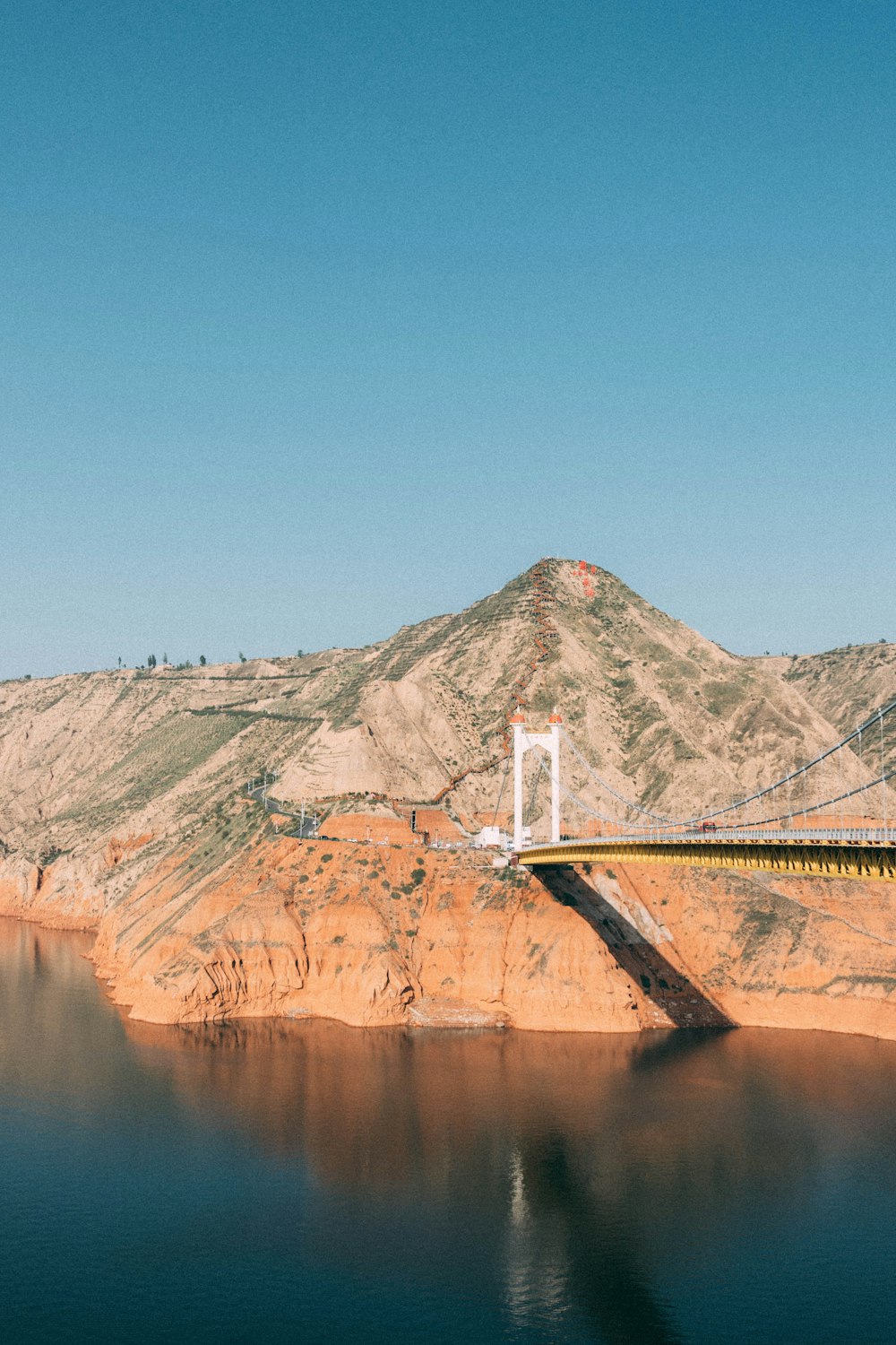 a bridge over a body of water with a mountain in the background