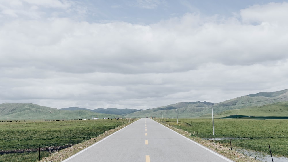 a long empty road with mountains in the background