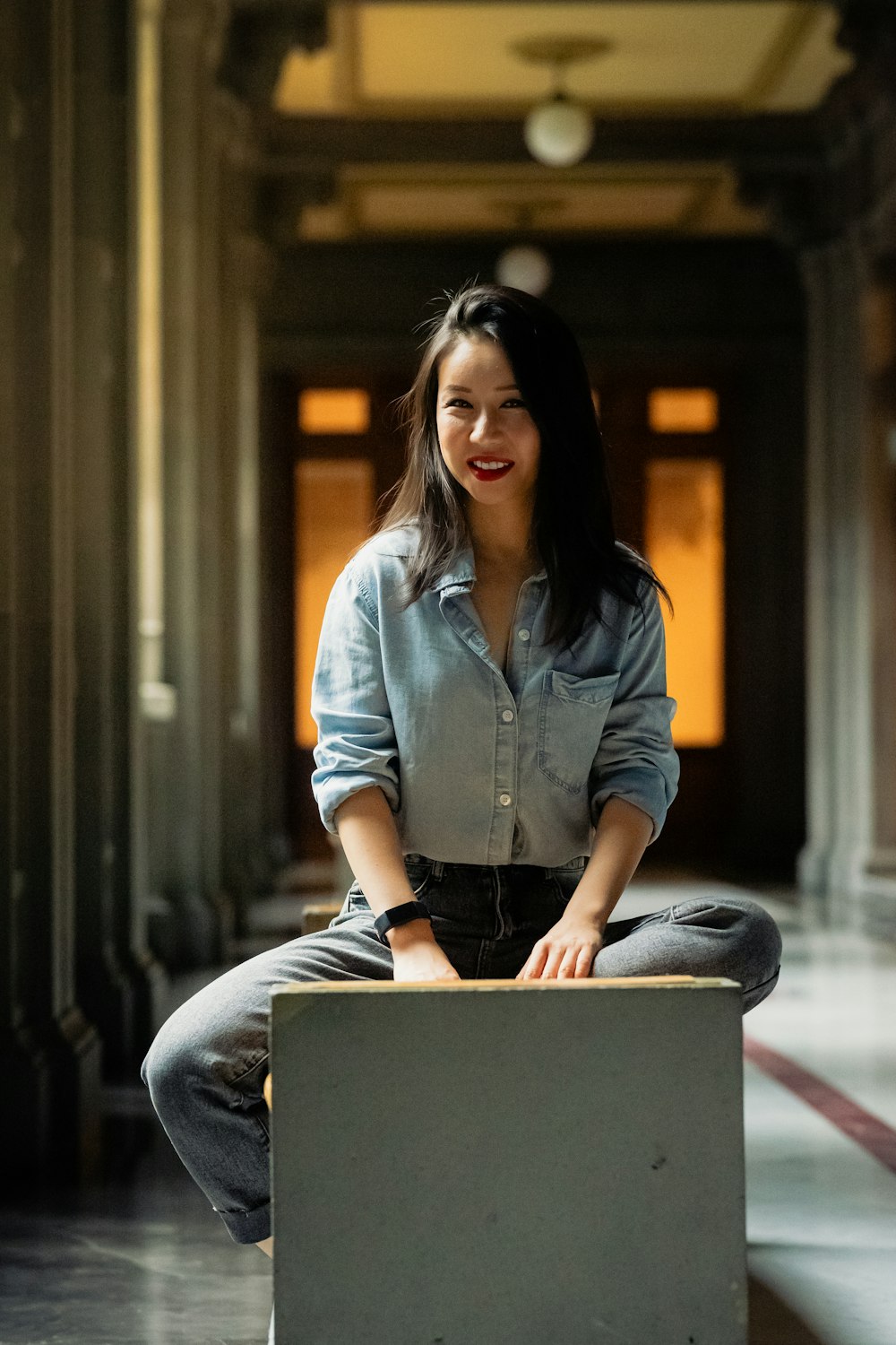 a woman sitting on top of a box in a hallway