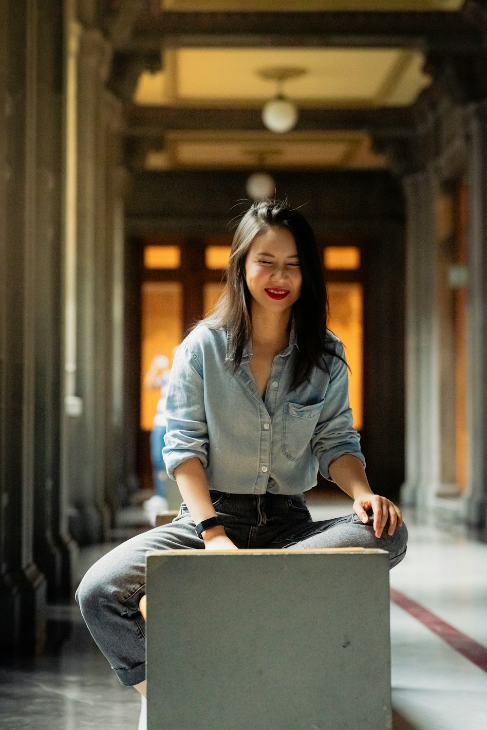 a woman sitting on top of a box in a hallway