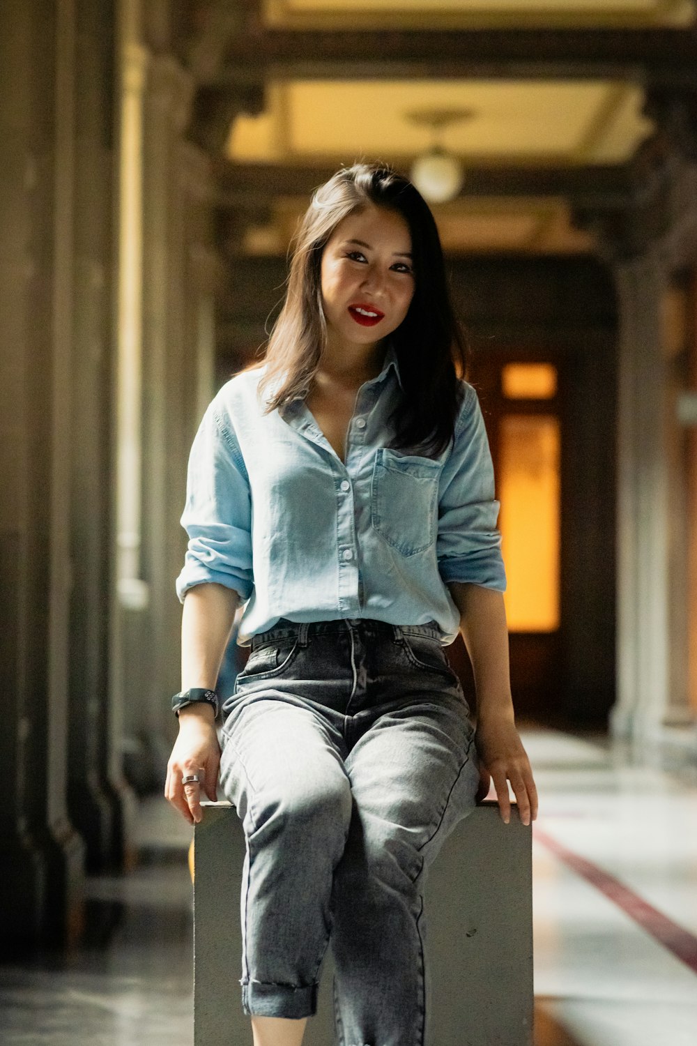 a woman sitting on top of a suitcase in a hallway