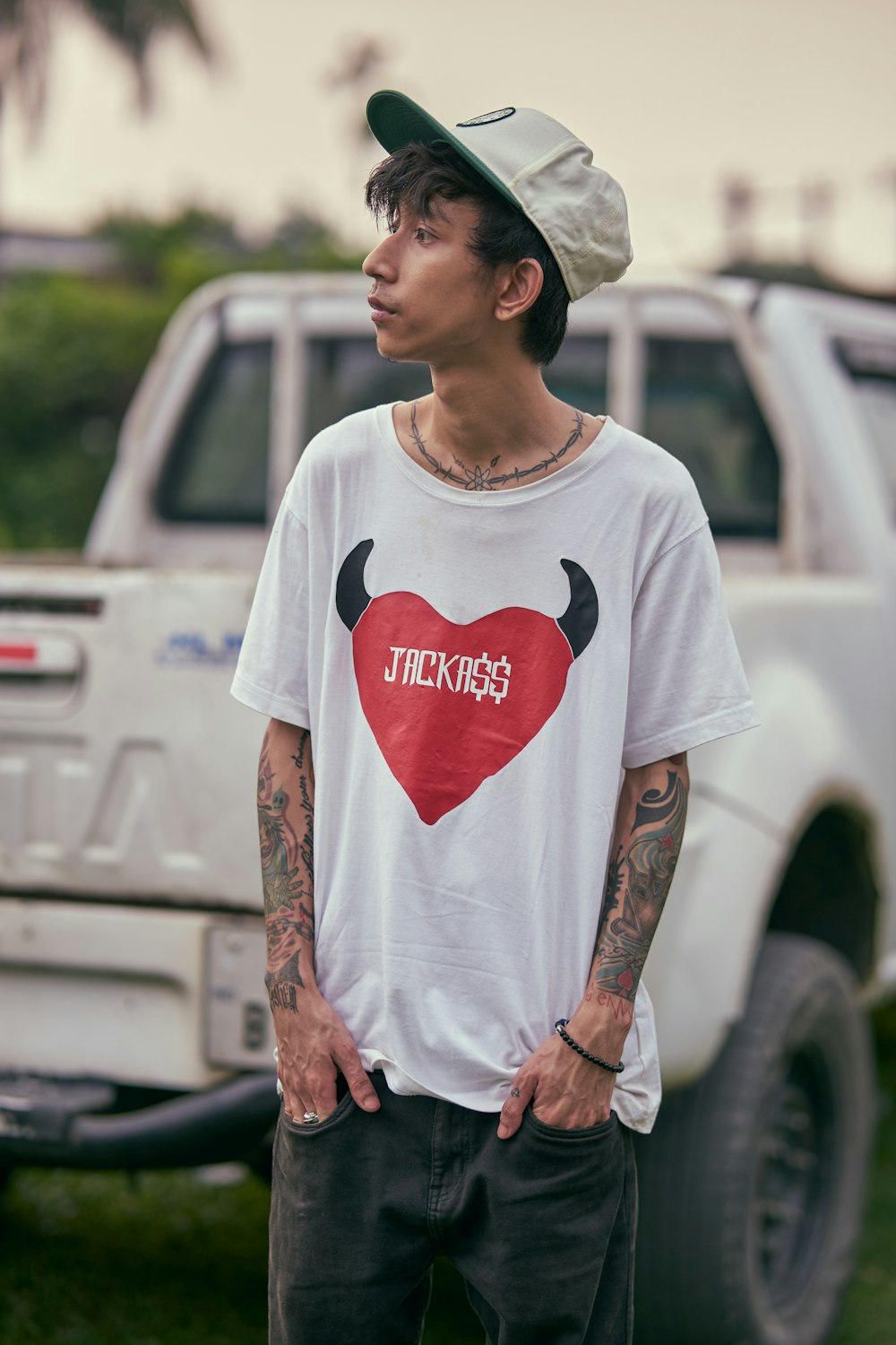 a man with a heart on his shirt standing in front of a truck