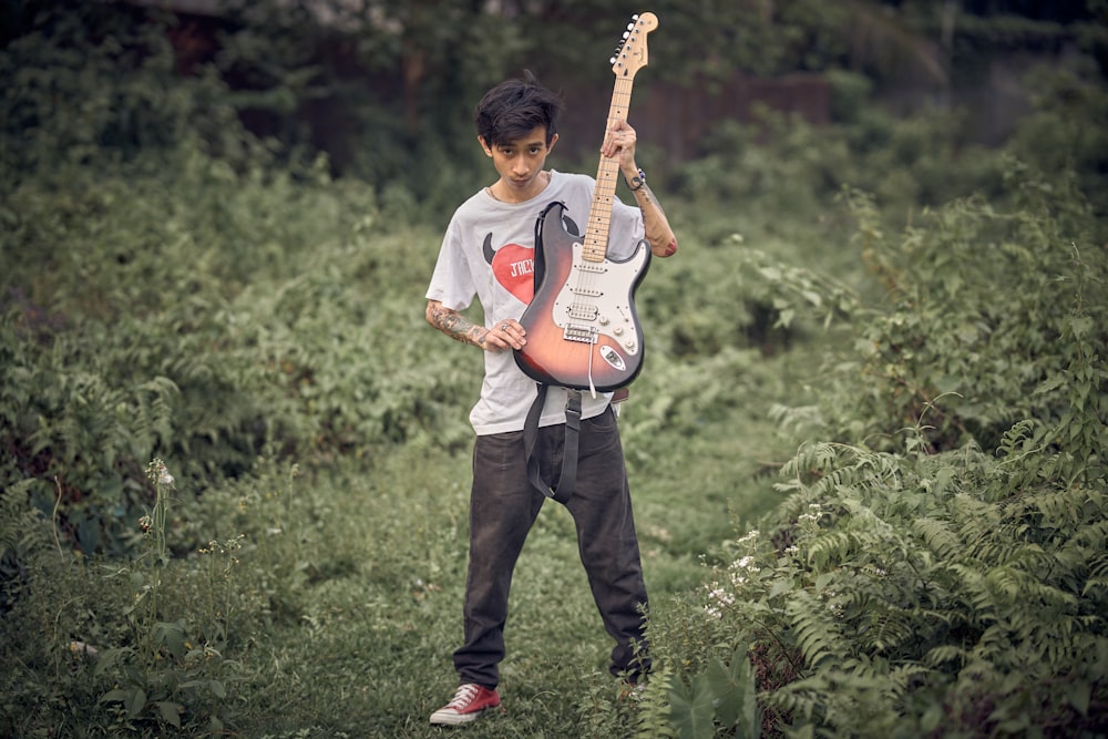 Un jeune homme tenant une guitare dans un champ