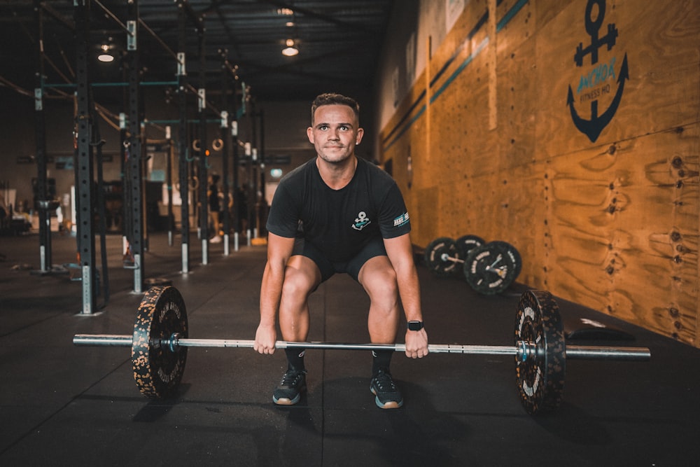 a man squatting on a barbell in a gym