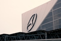 A large building with a modern architectural design features a prominent logo on its facade. The structure incorporates geometric patterns and metal elements, giving it an industrial look.