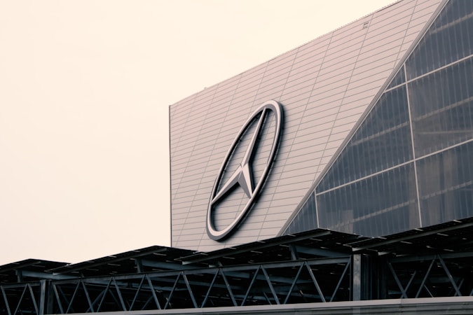 A large building with a modern architectural design features a prominent logo on its facade. The structure incorporates geometric patterns and metal elements, giving it an industrial look.