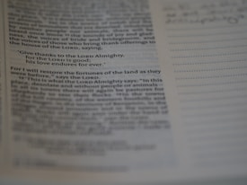 A close-up of a page from a book or Bible, highlighted with a specific verse stating gratitude to the Lord. The text is clear but the surrounding text is slightly out of focus.