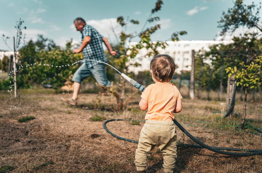 a little boy holding a hose in a field