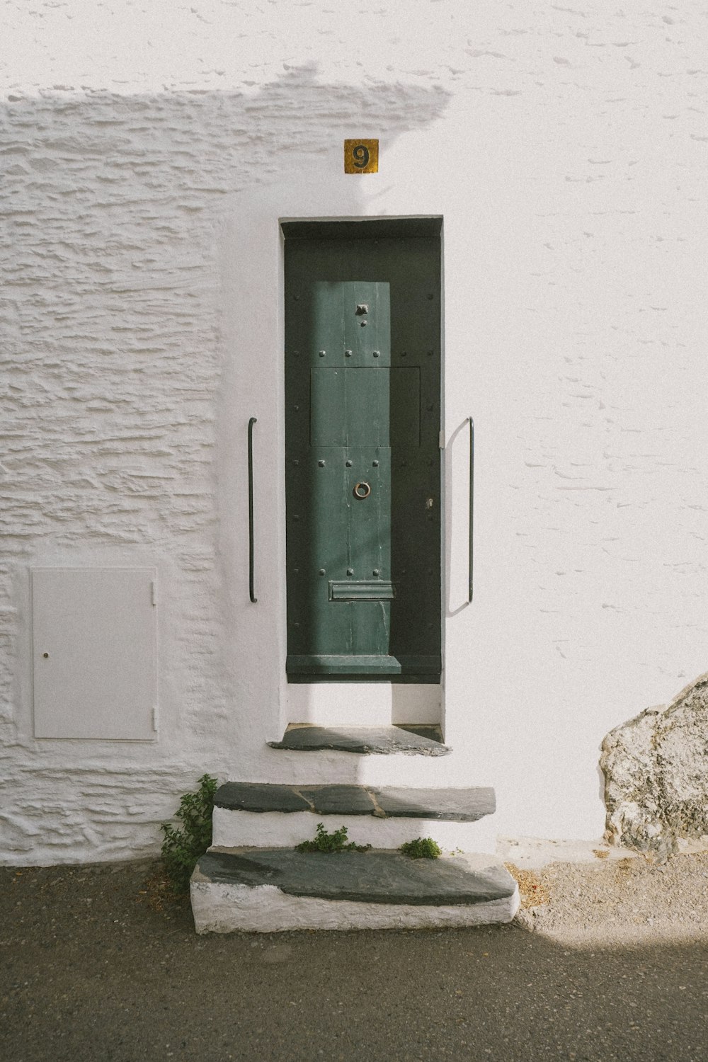 a white building with a green door and steps