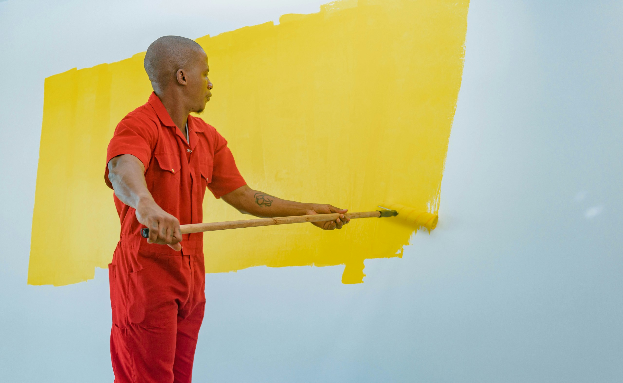 a man painting a wall with yellow paint