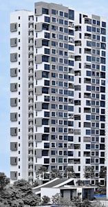 A modern high-rise residential building with a sleek facade consisting of a mix of large windows and geometric patterns. The structure is predominantly white with grey accents, surrounded by greenery and palm trees. The sky is clear, providing a clean backdrop for the building.