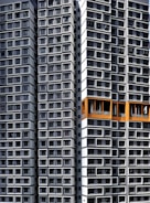 Tall residential buildings with a modern architectural design, featuring numerous windows arranged in an orderly, repetitive pattern. Some sections are highlighted with orange accents.