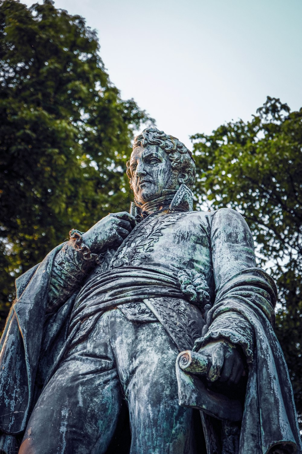 a statue of a man sitting in front of trees