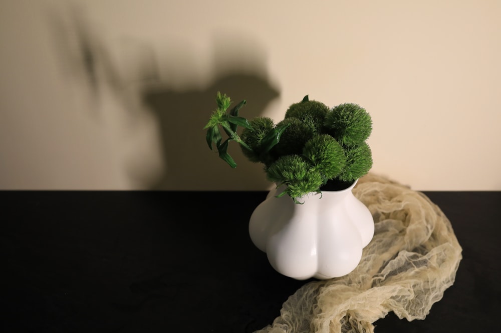 a white vase with a green plant in it