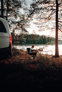 a van parked next to a lake with a person sitting at a table