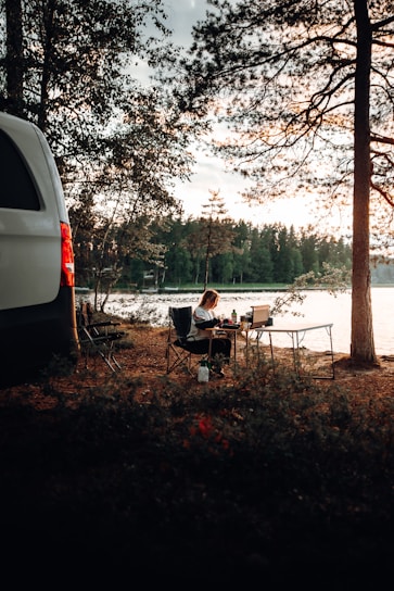 a van parked next to a lake with a person sitting at a table