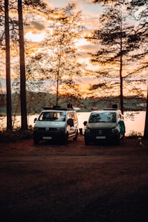 Team members analyzing survey data on laptops beside their field vehicles at sunset